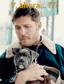 a man is holding a small dog with the words y ahora written above him