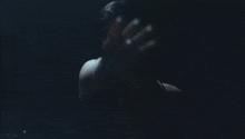 a woman in a black top is covering her face with her hands