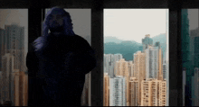 a man is standing in front of a window with a view of a city