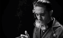 a young man in a leather jacket is smoking a cigarette .