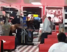a group of people are standing in a diner with a sign that says ' ice cream ' on it .