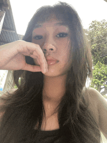 a woman with long hair is taking a selfie with her hand to her face
