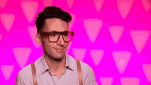 a man wearing glasses and suspenders is smiling and looking at the camera .