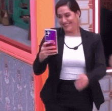 a woman in a suit is taking a picture of herself with her cell phone .