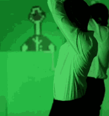 a man in a white shirt is stretching his arms in front of a green wall .