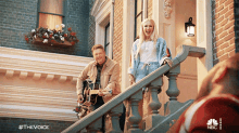 a man playing a guitar and a woman standing on a set of stairs with the hashtag #thevoice on the bottom