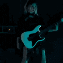 a woman is playing a guitar and singing into a microphone on stage .