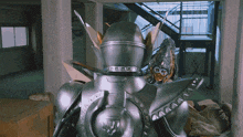 a silver robot is standing in an empty room next to a staircase