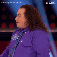 a man with long curly hair wearing a purple shirt and tie with a name tag that says mike