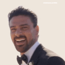a close up of a man in a tuxedo and bow tie smiling .
