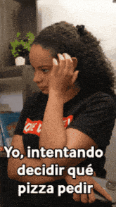 a woman with curly hair is wearing a black shirt that says " yo intentando decidir qué pizza pedir "