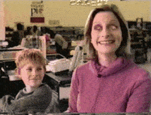 a woman in a pink sweater is smiling while a boy sits in front of a sign that says state pie