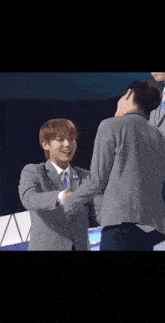 a man in a suit and tie is shaking hands with another man