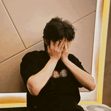 a man covering his face with his hands wearing a black t-shirt that says dd