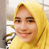 a close up of a woman wearing a yellow hijab smiling