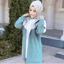 a woman wearing a hijab and a blue jacket is smiling