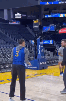 a man in a blue jersey is standing on a basketball court in front of a basketball hoop .
