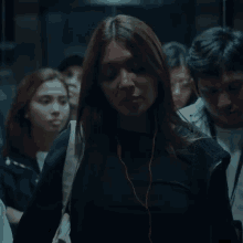 a woman wearing headphones is walking in a crowd
