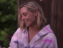 a woman wearing a purple robe is smiling and looking at her phone .
