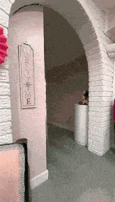 a hallway with a sign on the wall that says `` welcome '' and a brick archway .