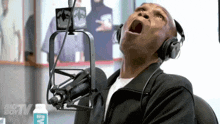 a man wearing headphones is sitting in front of a microphone with a big tv boy logo in the background
