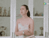 a woman standing in front of a white cabinet with a play button on the bottom right