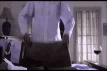 a man in a white shirt and tie is standing in a bedroom with a briefcase .