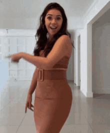 a woman in a brown dress is smiling and pointing at something