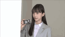 a girl in a suit is holding a cell phone with a sticker on it