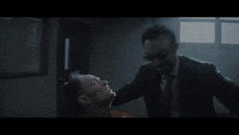 a man in a suit stands in a dark room