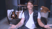 a young man is sitting in a chair with his arms outstretched in front of stuffed animals .
