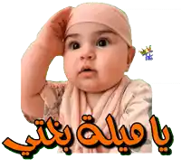 a baby is wearing a pink hat and a scarf and has arabic writing behind him