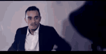a man in a suit and white shirt is talking to another man in a hat .