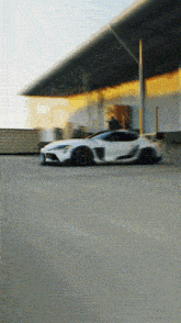 a white sports car is driving down a road in front of a building