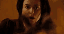 a woman with a scary face is standing in front of a fire in a dark room .