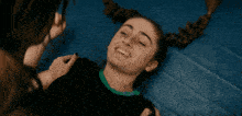 a girl with pigtails is smiling while laying on a blue mat