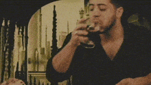 a man drinking a glass of wine while sitting at a table with pizza