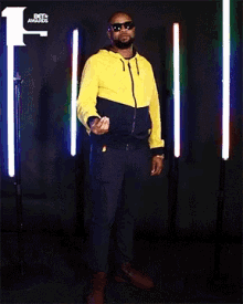 a man wearing sunglasses and a yellow jacket is standing in front of a bet awards sign