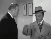 two men in suits and hats are standing next to each other in a room