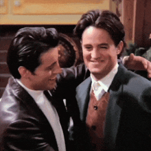 two men in suits are hugging and smiling at each other
