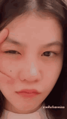 a close up of a woman 's face with thai writing on the bottom right
