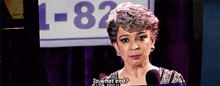 a woman is talking into a microphone in front of a sign that says `` to what end '' .