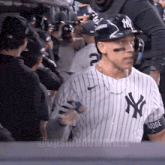 a man wearing a ny yankees jersey stands in a crowd