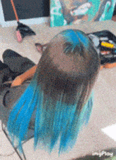 a person with blue hair is sitting on a chair