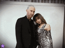 a man in a suit stands next to a woman in a snakeskin dress