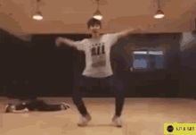 a man is dancing in a dance studio wearing a white shirt that says all .