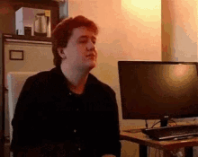 a man is sitting in front of a dell computer .