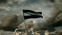 a flag on top of a mountain with a cloudy sky behind it