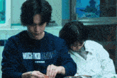 a man wearing a michiko london sweatshirt cooking with a woman