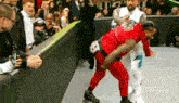 a man in a red suit is wrestling another man in a white suit on a wrestling ring .